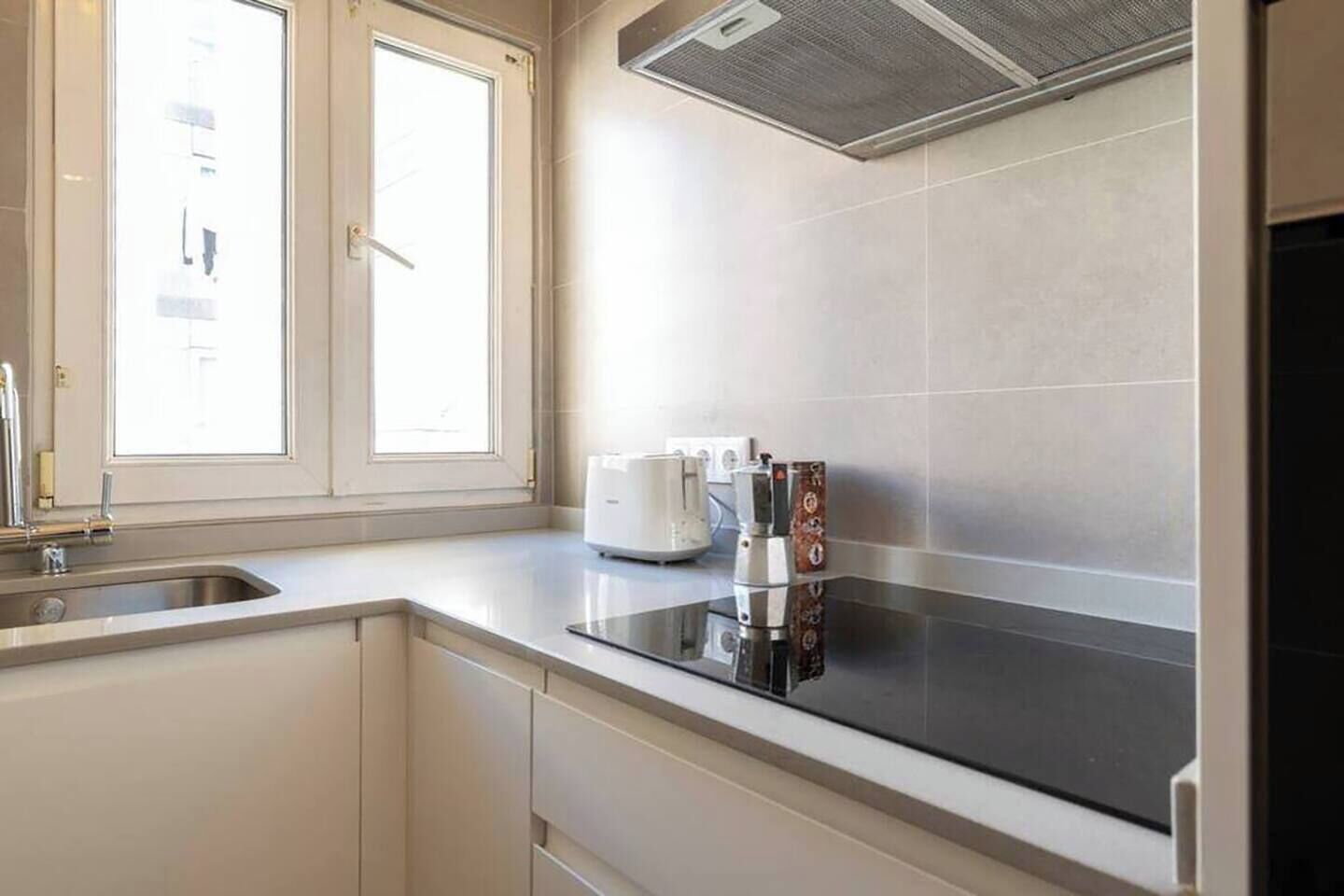 A kitchen with a window, a sink, a stove, and a coffee maker.