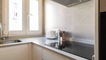 A kitchen with a window, a sink, a stove, and a coffee maker.