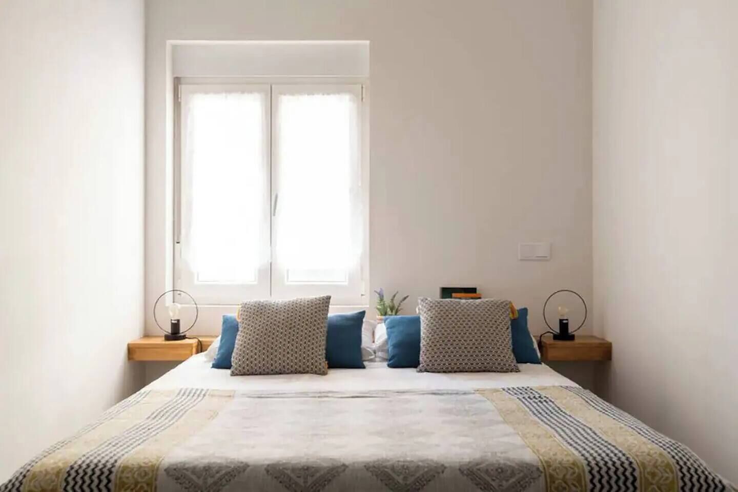 Un dormitorio con una cama, dos mesitas de noche y una ventana.