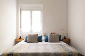 Een slaapkamer met een bed, twee nachtkastjes en een raam.