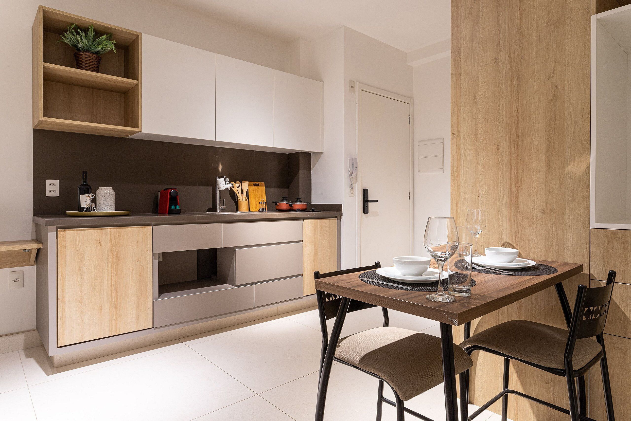 Una cocina moderna con armarios de madera, una mesa de comedor con sillas y una planta en maceta sobre la encimera.