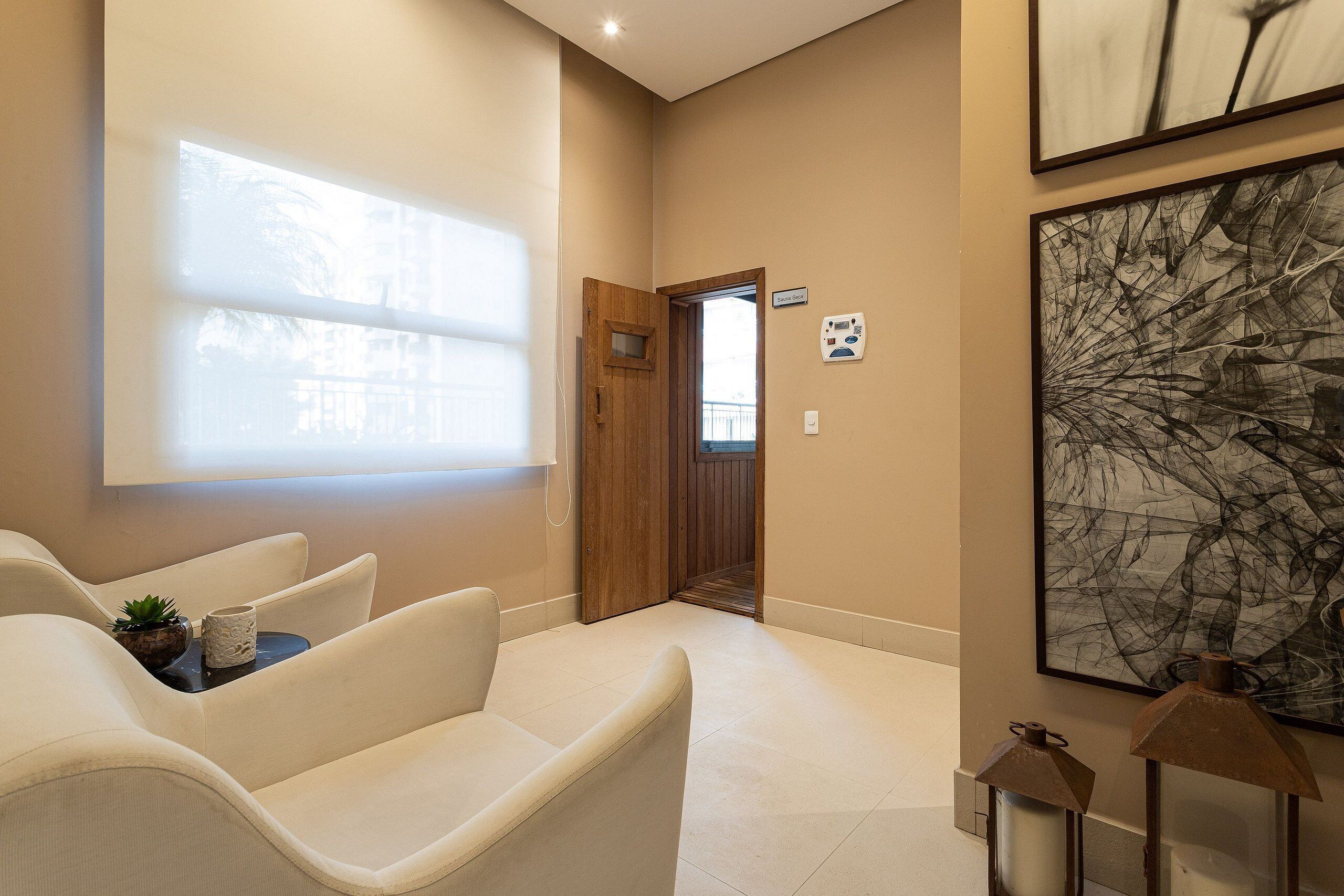 A modern living room with a sofa set, a small table with a plant, and a large abstract painting on the wall.