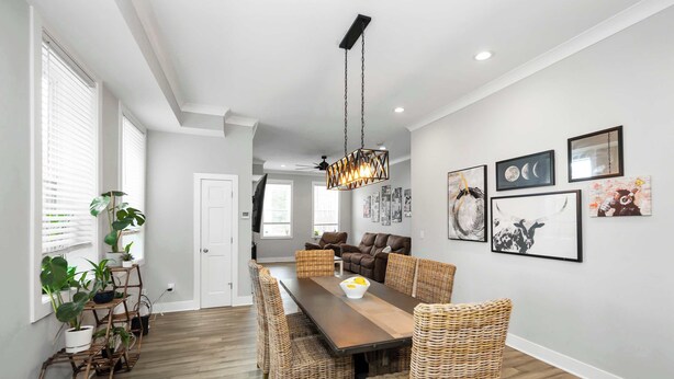 A dining area with a wooden table, wicker chairs, and a hanging light fixture. - Near UC + Cincinnati Zoo 3BR Sleeps 10 (Cincinnati)