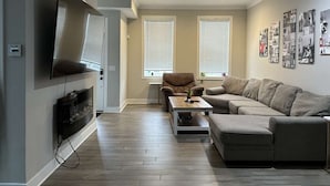 A living room with a flat-screen TV, a ceiling fan, a sofa, a coffee table, and a fireplace. - Near UC + Cincinnati Zoo 3BR Sleeps 10 (Cincinnati)