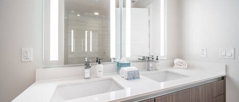 A modern bathroom with two sinks, a large mirror, and wooden cabinets.