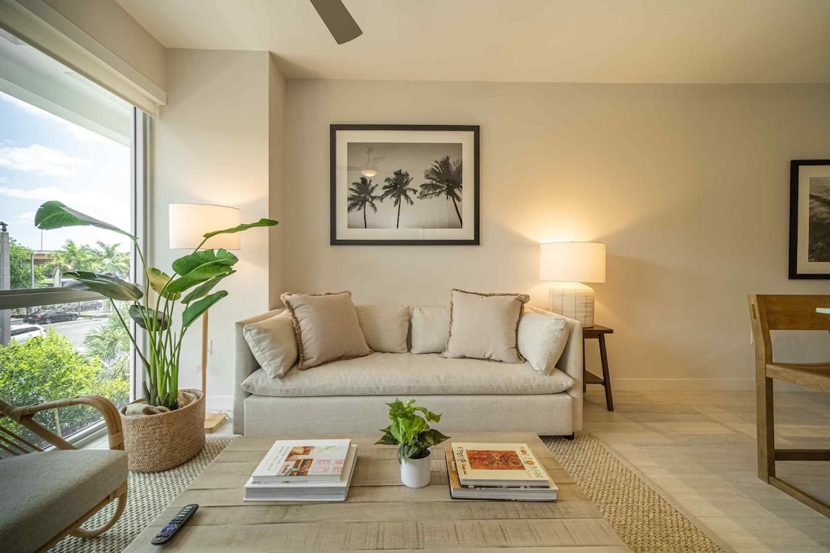 A living room with a sofa, two lamps, a framed picture, and a potted plant.