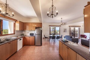 A modern kitchen with wooden cabinets, stainless steel appliances, and a central island. - Villa Korona - Three Bedroom Villa, Sleeps 6 (Neo Chorio)