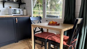 A compact kitchen with a microwave, a small fridge, and a wooden dining table with chairs.