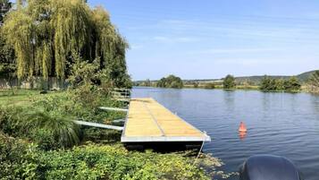 A wooden dock extending into a calm river, surrounded by lush greenery and trees.