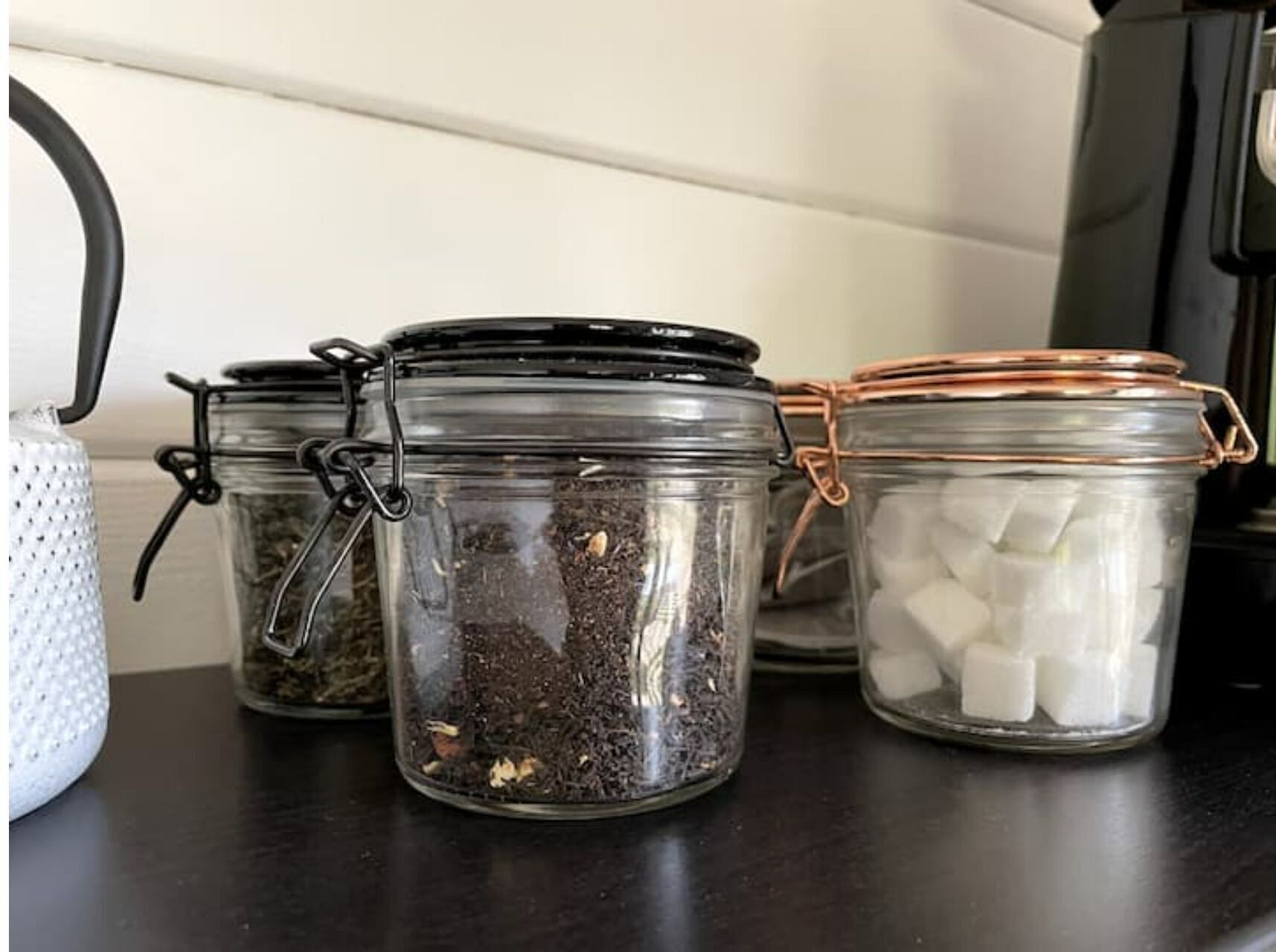 Três potes de vidro com tampas de metal em uma bancada de cozinha.