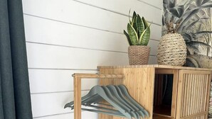 A wooden shelf unit with a hanging rack, a potted plant, and decorative baskets.