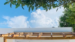 Een gebouw aan het strand met een houten terras, een overdekte zithoek en een zwembad.