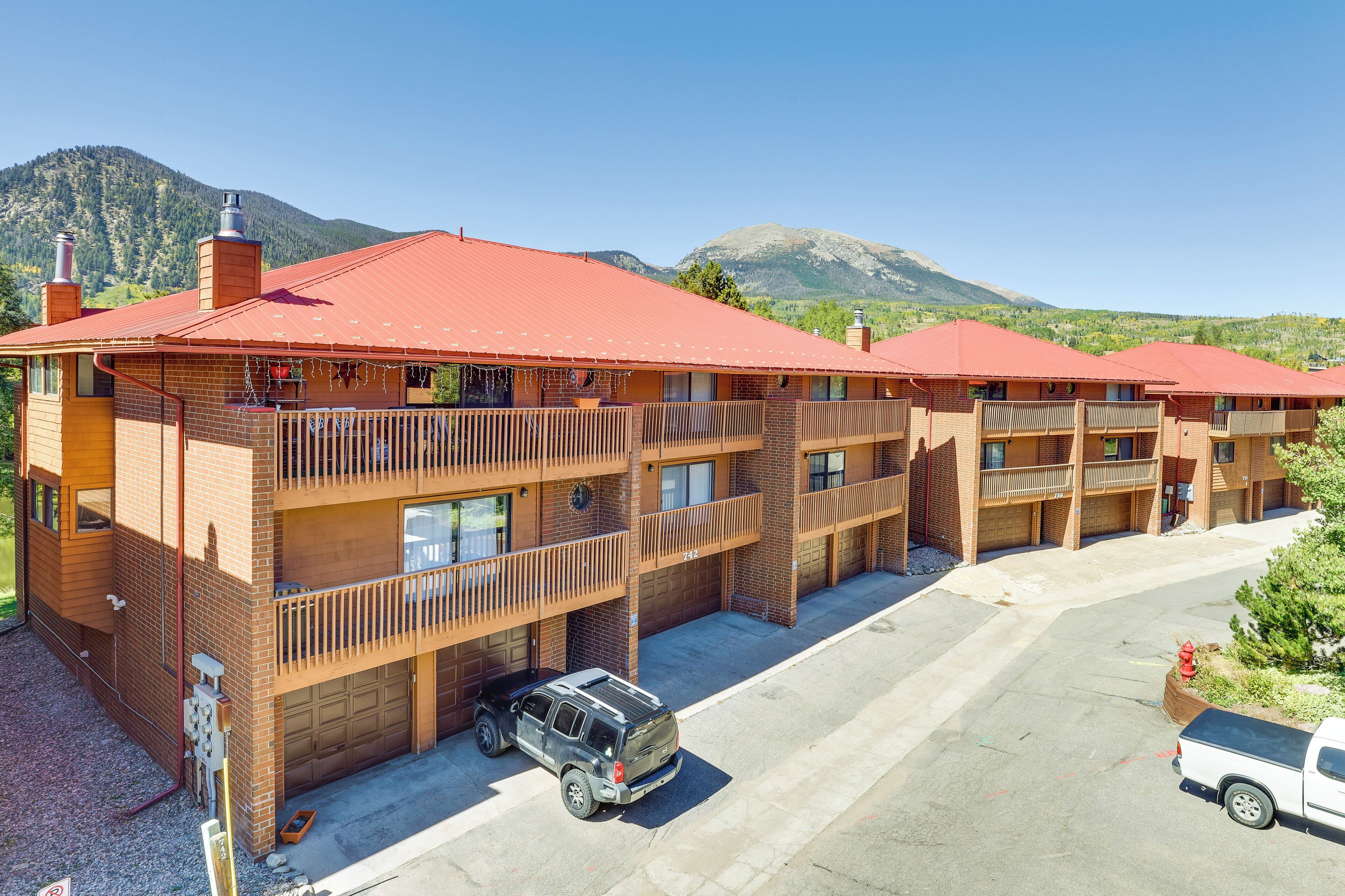Et flereetages motel med murstensfacade og røde tage, med altaner og parkeringsområde.