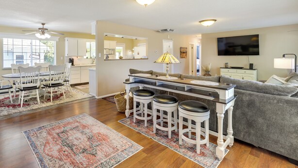 A spacious living area with a kitchen, dining table, and bar stools.