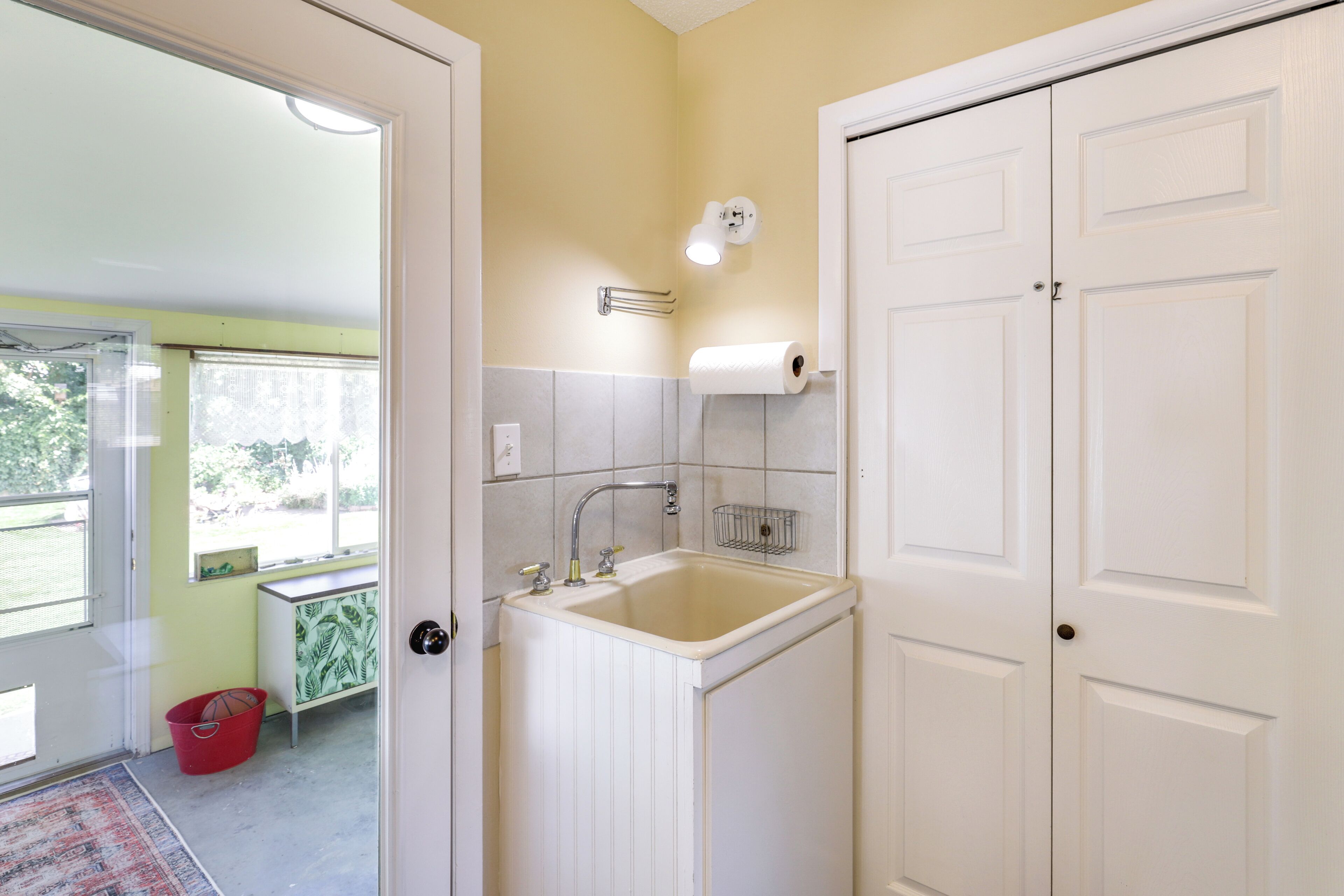 A bathroom with a sink, toilet paper holder, and a door.