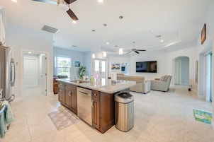 A spacious kitchen with a central island, a dining area with a sofa, and a living room with a TV.