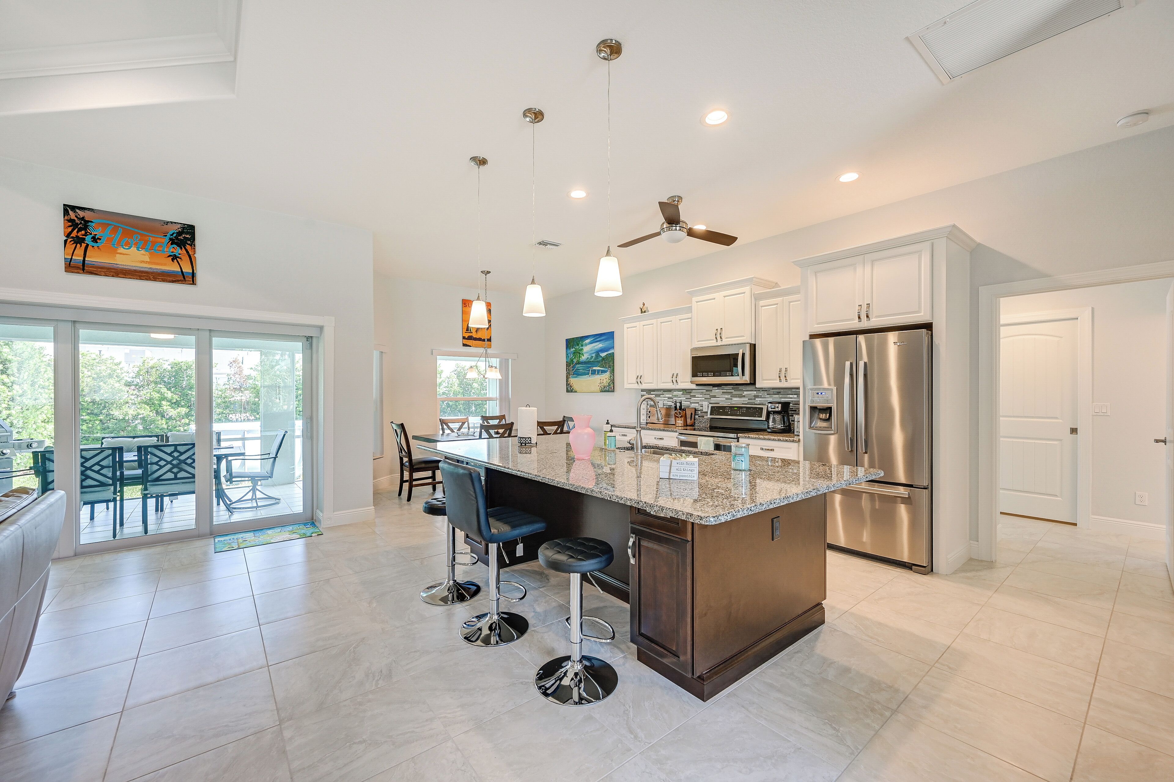 A modern kitchen with a large island, stainless steel appliances, and a ceiling fan.