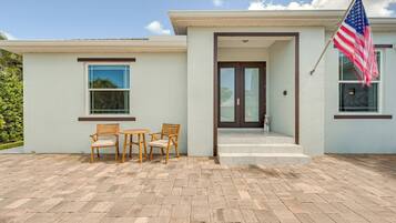 A modern house with a patio, two wooden chairs, a small table, and an American flag.