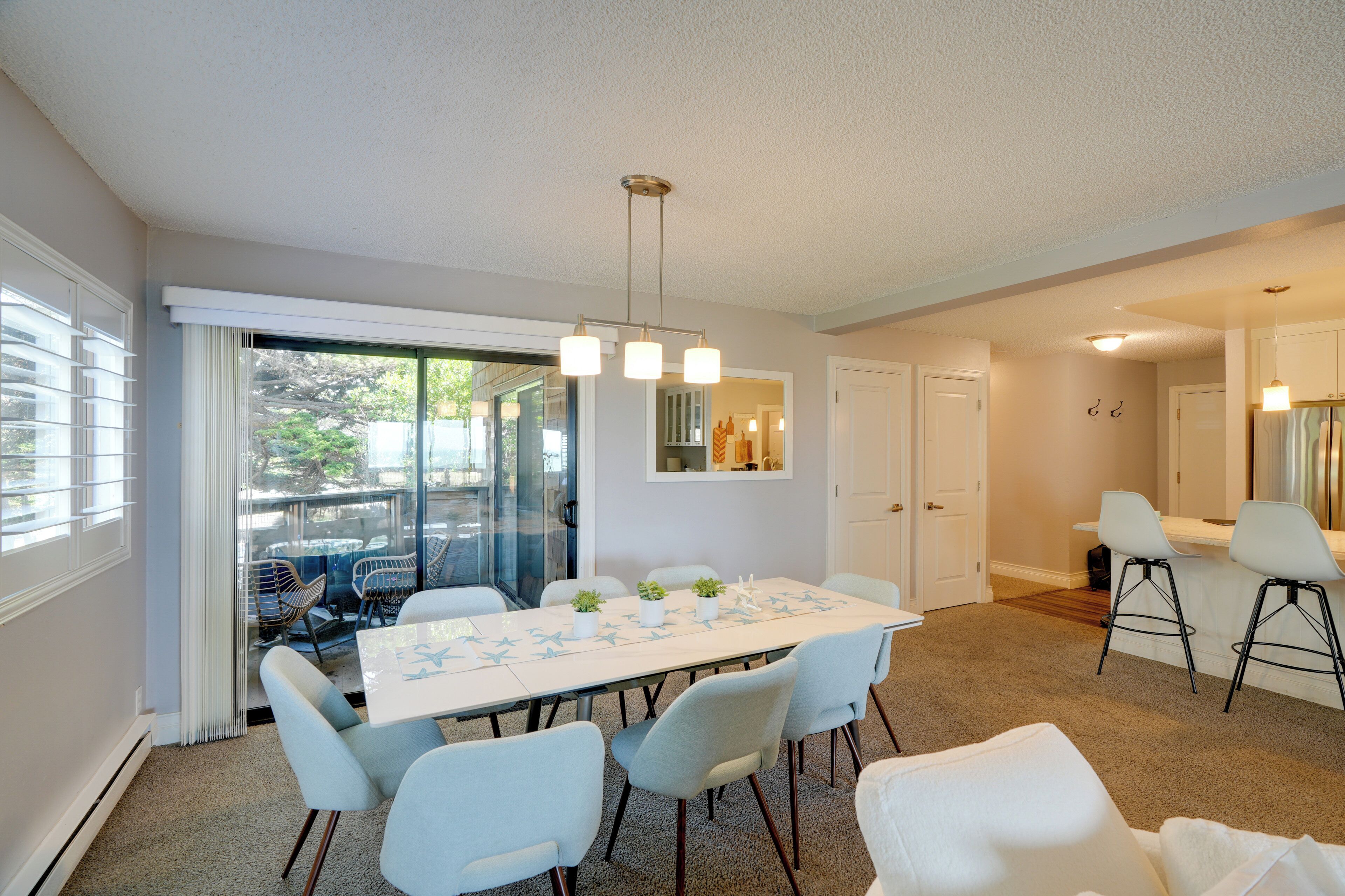 A dining area with a long table, chairs, and a hanging light fixture.
