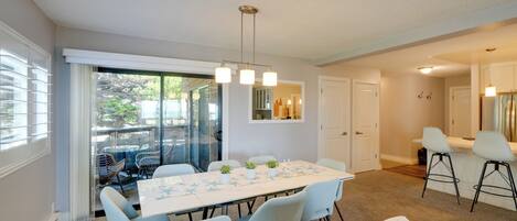 A dining area with a long table, chairs, and a hanging light fixture.