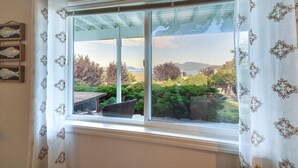 A window with a view of a garden and mountains.