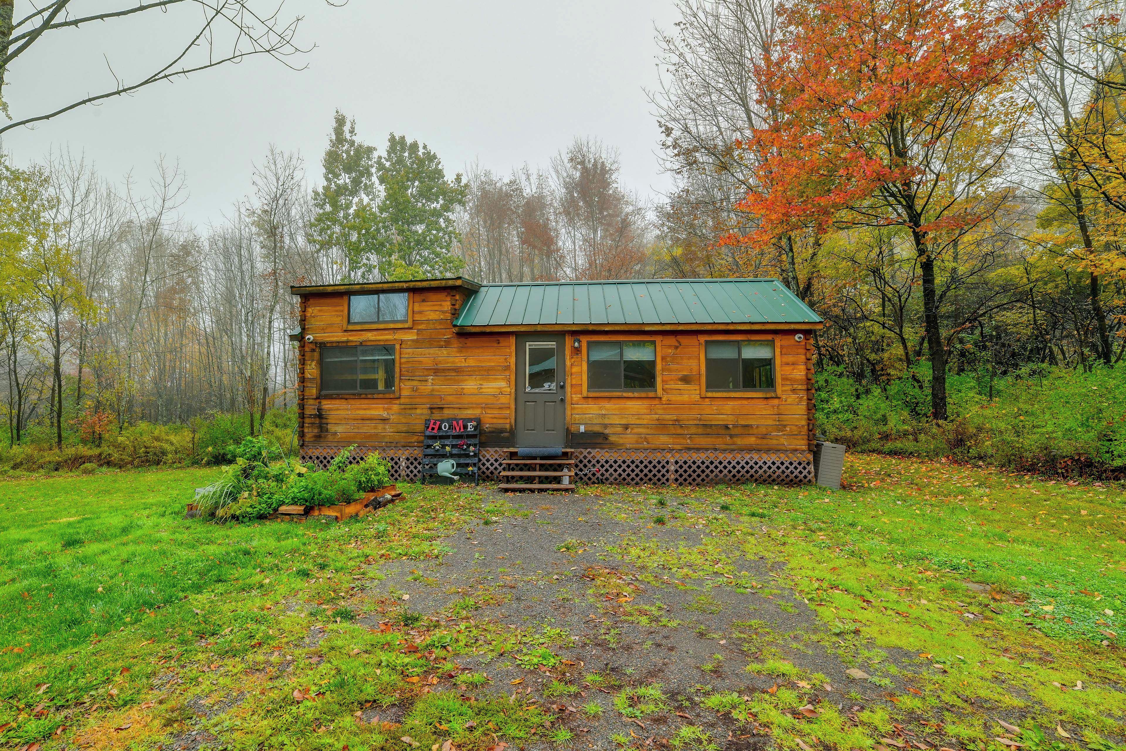A wooden cabin with a green roof, a front porch, and a 'HOME' sign.