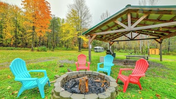 A covered outdoor seating area with Adirondack chairs and a fire pit.