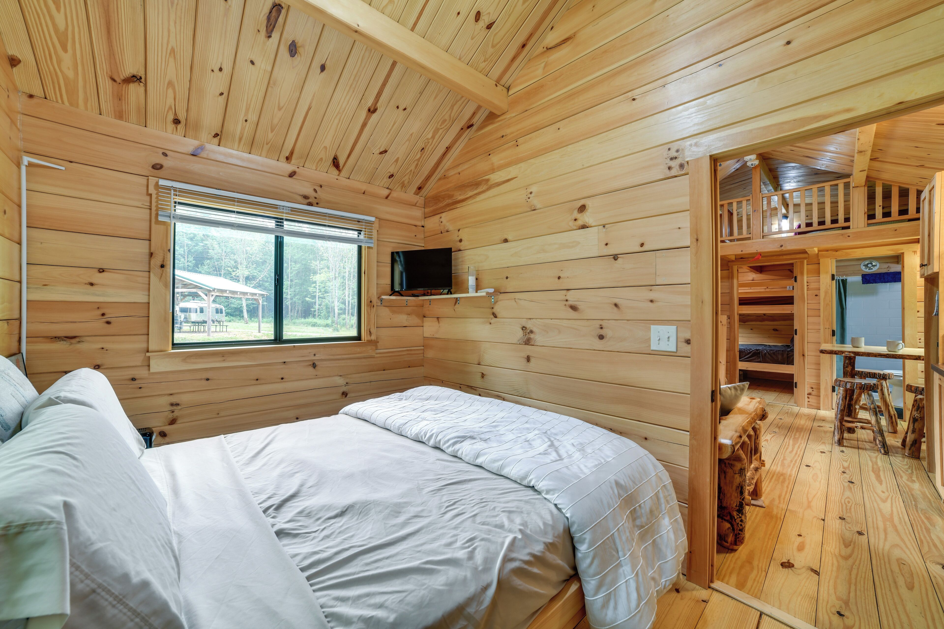A wooden cabin with two beds, a TV, and a balcony.
