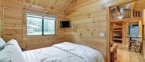 A wooden cabin with two beds, a TV, and a balcony.