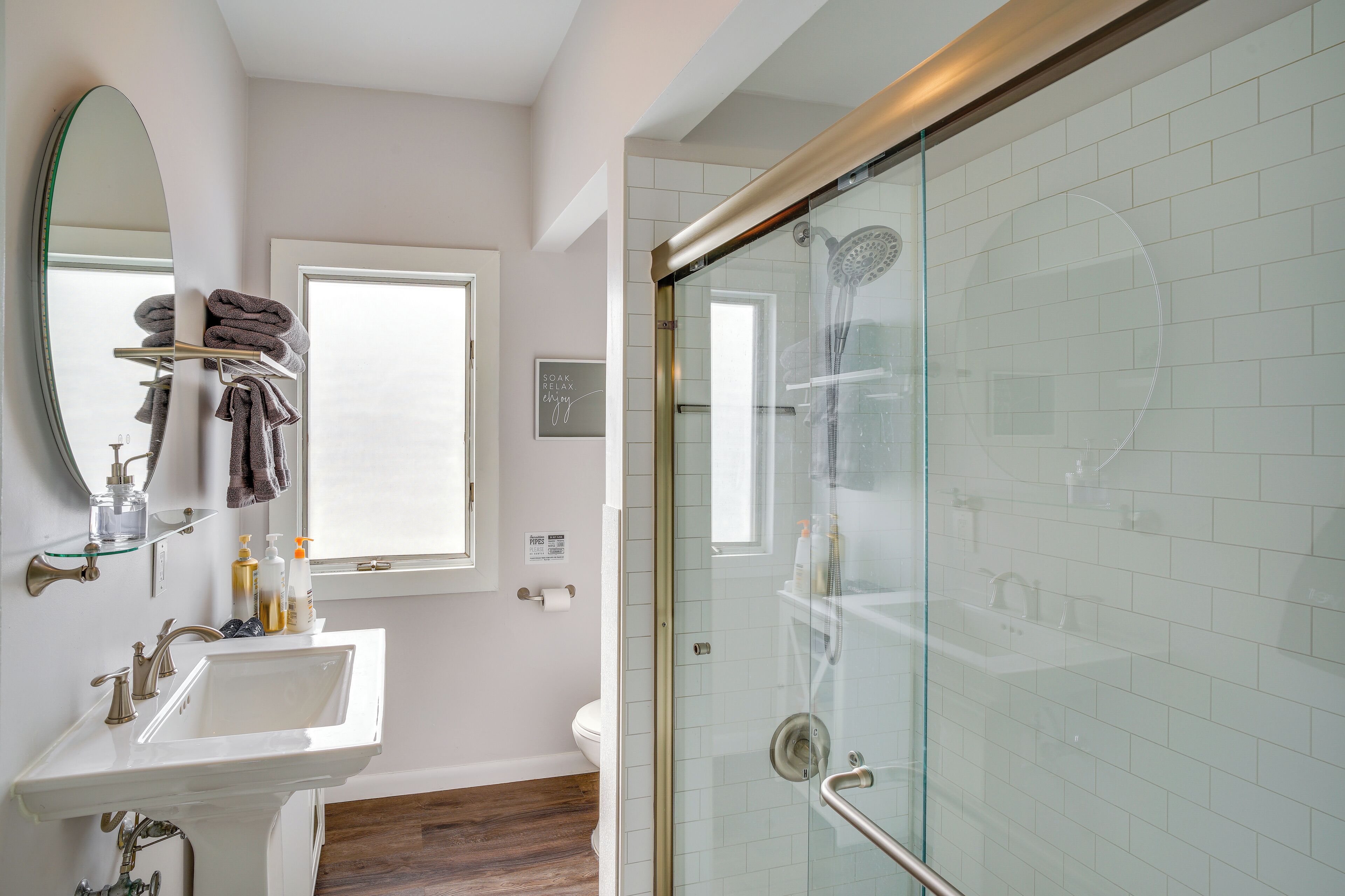 A bathroom with a sink, mirror, and glass shower enclosure.