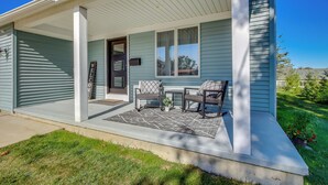 A house with a covered porch, two chairs, a small table, and a welcome sign. - Steps to Lake Michigan: Manitowoc Home w/ Fire Pit (Manitowoc)