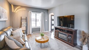A modern living room with a leather sofa, a wooden coffee table, and a television on a wooden cabinet. - Steps to Lake Michigan: Manitowoc Home w/ Fire Pit (Manitowoc)