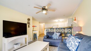 A living room with a TV, sofa, and ceiling fan. - Oak Island Vacation Rental ~ 1 Block to Beach! (Oak Island)