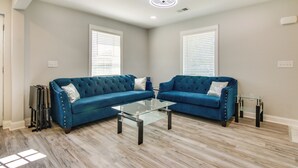 A living room with two blue sofas, a glass coffee table, and a flat-screen TV on a stand. - Updated Home - Walk to Salisbury University! (Salisbury)
