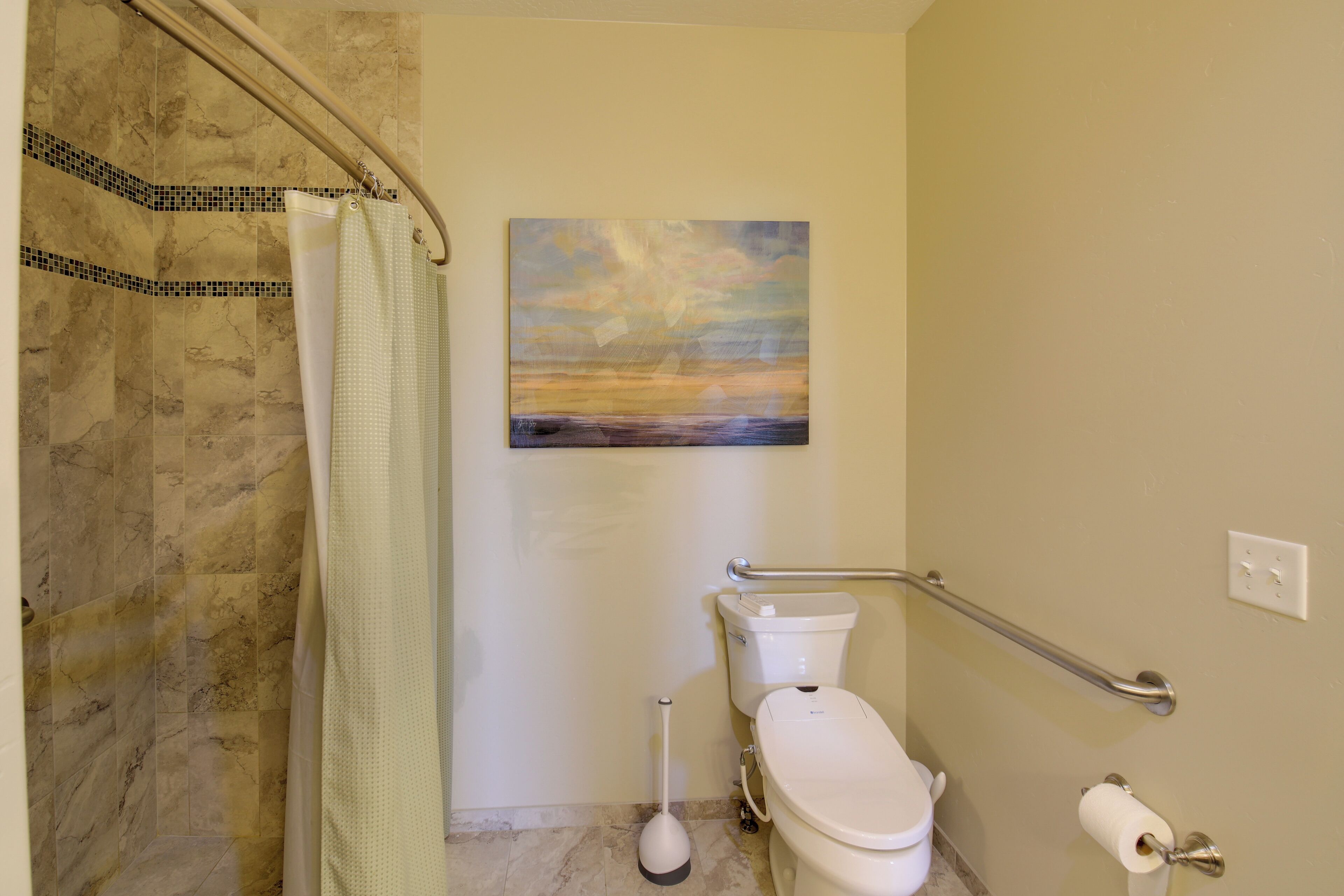 A bathroom with a shower, toilet, and handrail.