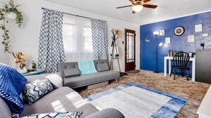 A living room with a sofa, patterned cushions, a blue rug, a ceiling fan, and a wall with framed pictures. - Private Deck & Yard: Pet-friendly Craig Townhome! (Craig)