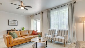 A living room with a brown leather sofa, two striped armchairs, a round coffee table, and a ceiling fan. - Charming Navarre Townhome: 5 Mi to Beach! (Navarre)