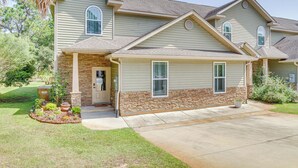 A two-story house with a stone foundation, a front porch, and a well-maintained lawn. - Charming Navarre Townhome: 5 Mi to Beach! (Navarre)