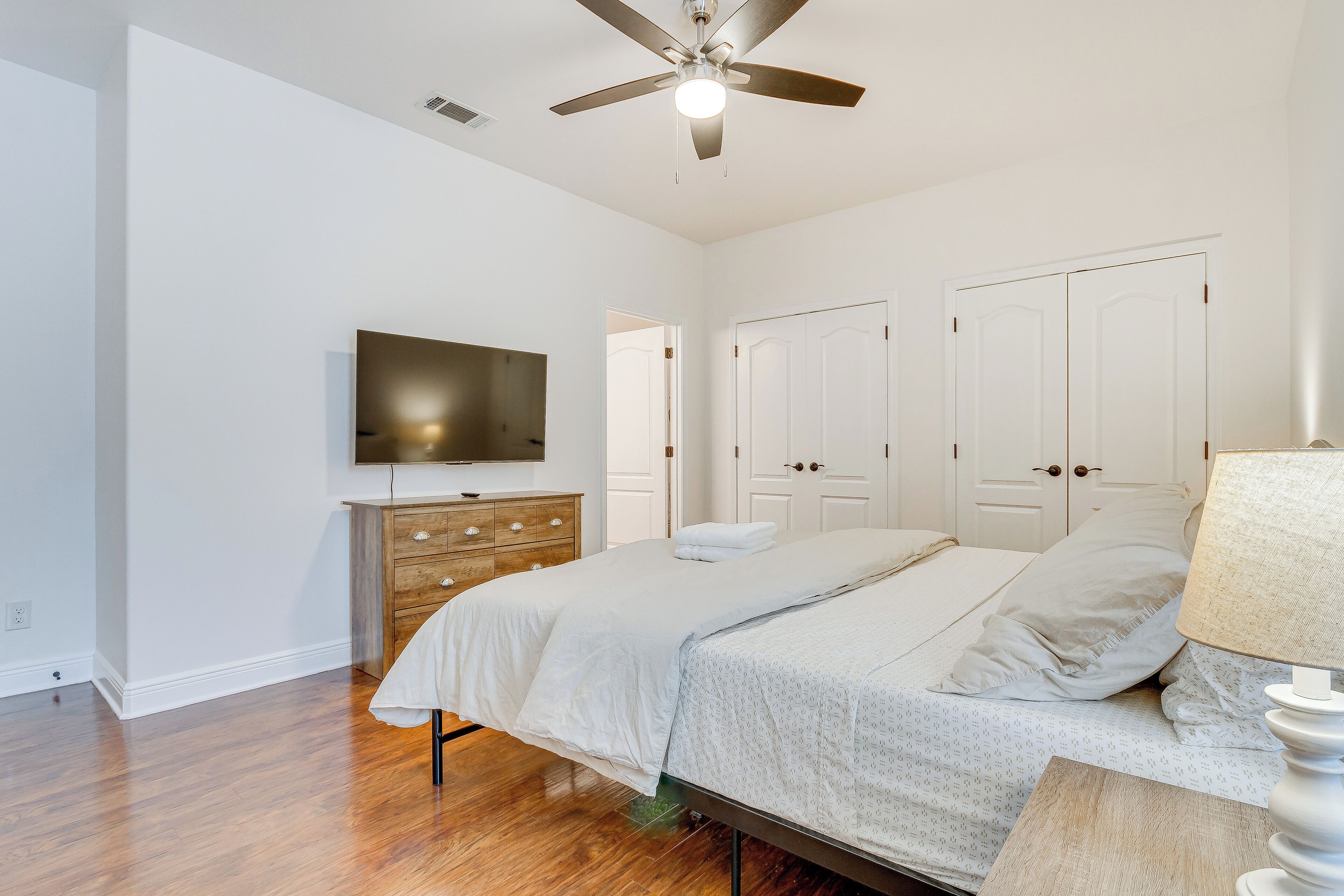 Une chambre à coucher comprenant un lit, une commode, un téléviseur et un ventilateur de plafond.