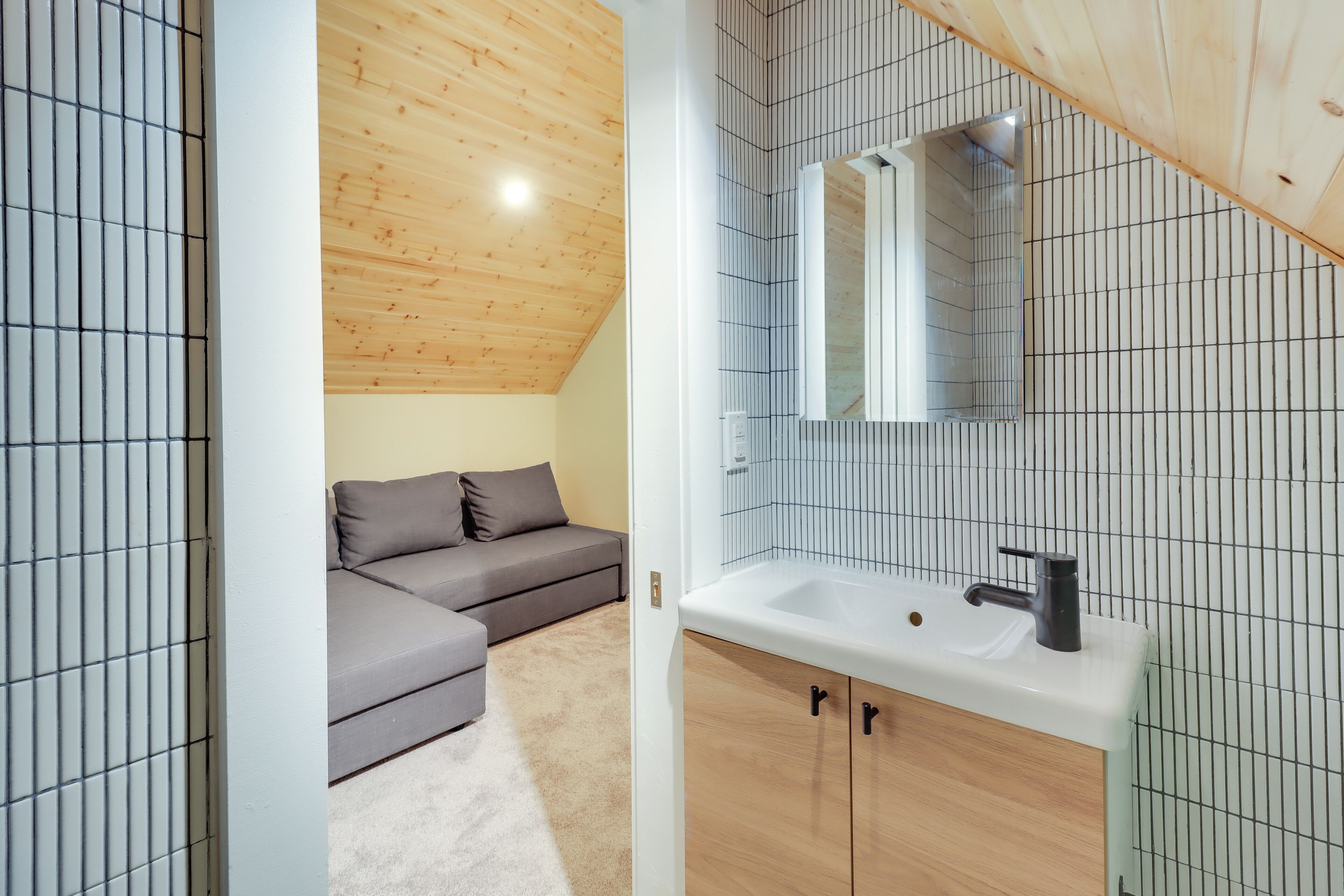 A modern bathroom with a wooden ceiling, a white sink, and a mirror above it.
