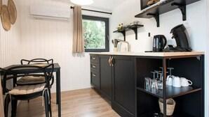 Una cocina moderna con armarios oscuros, una mesa de comedor de madera y una lámpara colgante.