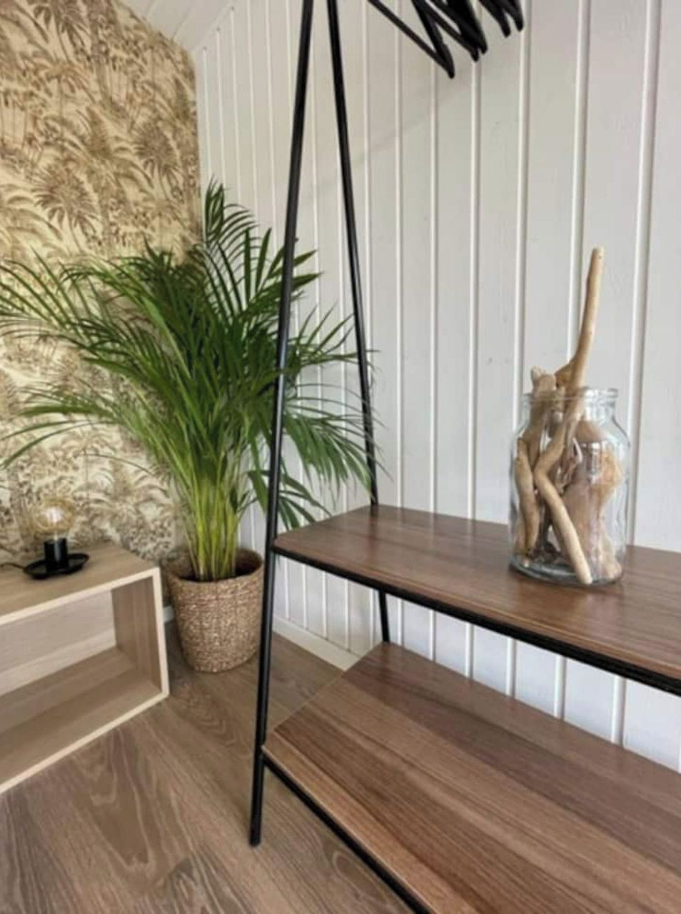 Une étagère en bois sur laquelle se trouve un bocal en verre contenant des objets décoratifs.