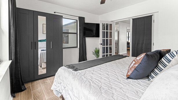 Une chambre avec un lit, un ventilateur de plafond et une vue sur l’extérieur.