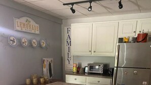 Een keuken met witte kasten, een granieten aanrecht, een koelkast, een magnetron en een koffiezetapparaat.