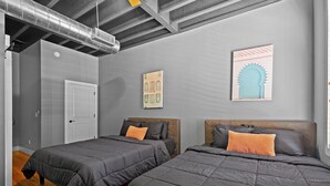 A bedroom with two beds, a door, and a ceiling with exposed ductwork. - Downtown Chattanooga Loft in the Heart of the City (Chattanooga)