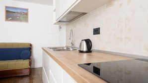 A compact kitchen with a wooden countertop, stainless steel sink, and a kettle.