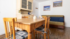 A cozy room with a wooden dining table, chairs, a sofa, and a cabinet with glass doors.