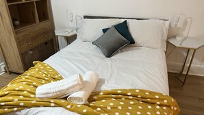 A neatly made bed with a polka dot blanket, pillows, and a rolled towel. - Apartment in Leicester- Doublebed-citycentre-wifi (Leicester)