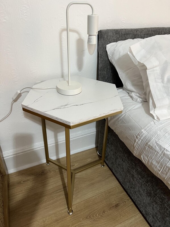 A small bedside table with a white lamp, a power cord, and a wooden floor. - Apartment in Leicester- Doublebed-citycentre-wifi (Leicester)