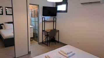 Een hotelkamer met een bed, een bureau, een stoel, een televisie en een douche.